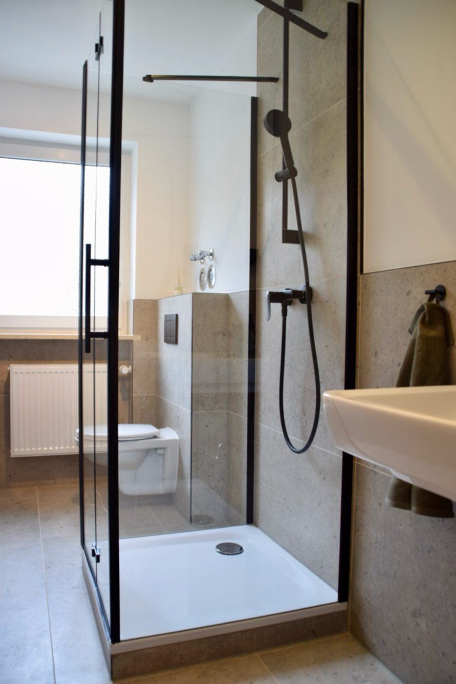 Fertiges Badezimmer mit bodengleicher Dusche, WC und Waschbecken in Steinoptik